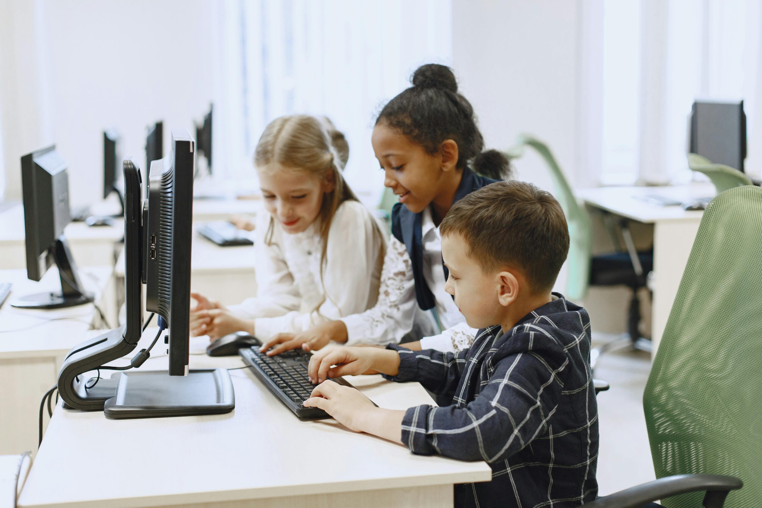 Drei Kinder lernen gemeinsam an einem Computerarbeitsplatz